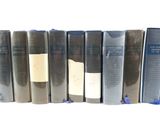 several books are lined up in a row on a white surface