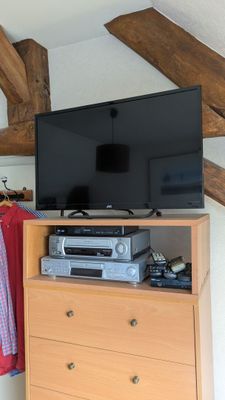 une télévision posée sur une commode dans une pièce au plafond en bois