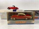 two red and white model cars in a box on a table