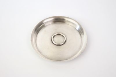 a silver plate with a ring on it on a white surface