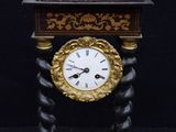 a clock that is sitting on a stand with a black background