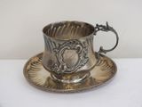 a silver cup and saucer on a saucer