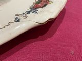 a white plate with a flower design on it on a pink table cloth