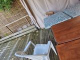 a white chair sitting on a wooden deck next to a bed