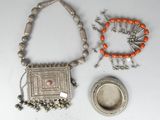 two pieces of silver and orange jewelry on a white surface