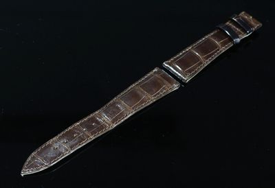 une image représentant une montre avec un bracelet en cuir marron sur un fond noir