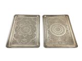 two silver trays with intricate designs on them on a white background