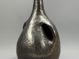 un vase en argent troué, posé sur une table