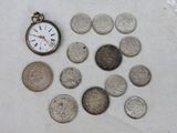 beaucoup de pièces de monnaie et une montre de poche sur la table