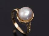 a gold ring with a white pearl in the center