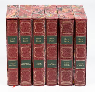 quatre livres rouges à la couverture verte sont posés sur une surface blanche