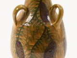 un vase marron orné de pommes de pin sur fond blanc