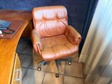 a brown leather chair sitting in front of a computer desk