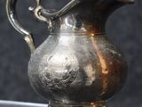 un pichet en argent posé sur une table en verre