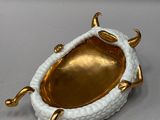 a white and gold dish with a gold handle