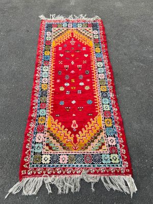 a red rug with fringes on the ground