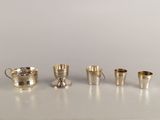 Plusieurs coupes et tasses en argent sont alignées sur une table