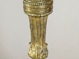 a gold vase on a stand with a flower on it
