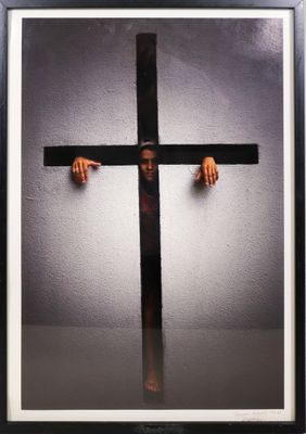 une photo d'une personne tenant une croix devant un mur