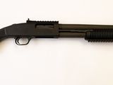 un fusil noir posé sur une table blanche, sur fond blanc