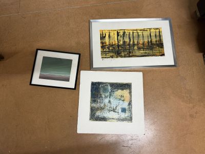 trois photos encadrées posées par terre dans une pièce