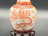 un vase orange et blanc posé sur un socle en métal