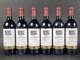 six bottles of wine are lined up in a row on a table