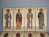 six religious icons of saints in different colors on a shelf