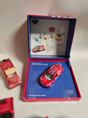 une petite voiture rouge dans une boîte rouge, à côté d'autres petites voitures