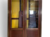 une armoire en bois avec une porte vitrée et une valise