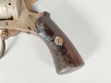 a silver revolver with a wooden handle on a white surface