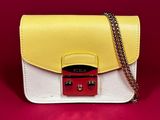 a white and yellow purse with a chain on a red background