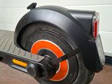 a black scooter with orange wheels parked in front of a garage