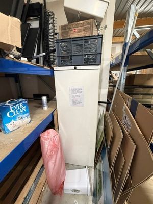un réfrigérateur blanc au milieu d'une pièce remplie de cartons