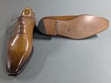 men ' s tan leather shoes with laces on a grey surface