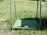 a green platform in the middle of a grassy field