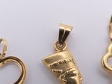 three gold pendants of different shapes and sizes on a white surface