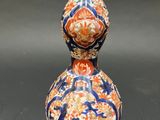an orange and blue vase sitting on top of a black table