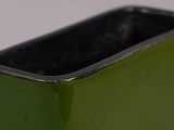 a green vase with a black rim sitting on a table