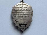 a silver heart shaped pendant with writing on it