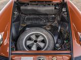 a small orange car with a large engine in it ' s trunk