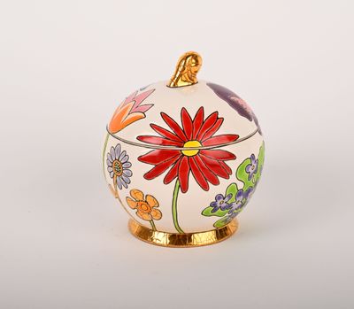 une image représentant une boîte ornée de fleurs blanches et rouges, posée sur un socle doré
