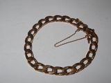 a close up of a gold chain bracelet on a white surface