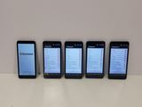 four cell phones are lined up on a table with a white background