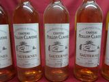 six bottles of wine are lined up in a row on a pink background