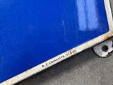 a blue sign sitting on the ground next to a building