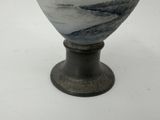 a vase that is sitting on a stand on a white surface