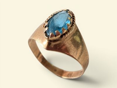an image of a gold ring with a blue topaz stone