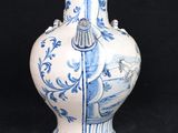 a blue and white vase sitting on a black surface