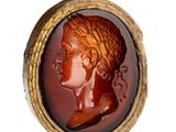 an image of a red and gold ring with a woman ' s profile